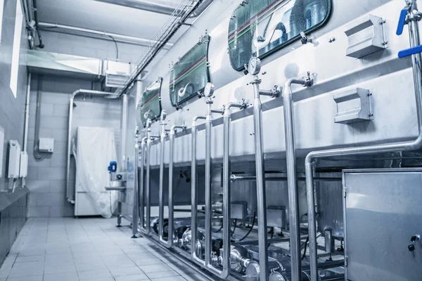Lavadora automática transportadora con botellas de plástico azul en el interior de la fábrica de fabricación de agua —  Fotos de Stock