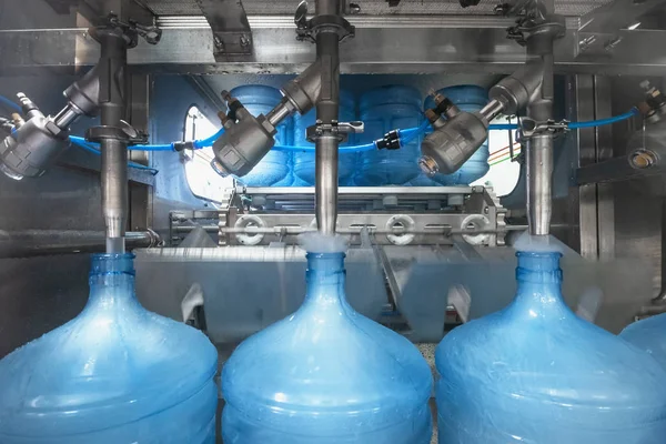 Línea de producción de agua potable. Máquina automatizada industrial para llenar botellas de plástico o galones con agua potable, de cerca —  Fotos de Stock