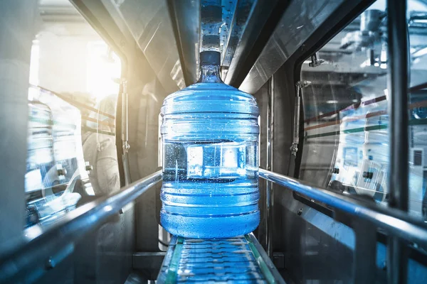 Plastic bottle or gallon of purified drinking water inside automated conveyor production line. Water factory
