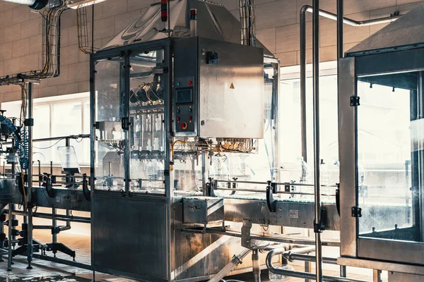 Taller interior con máquinas y transportador para la producción y embotellado de agua potable purificada en botellas de plástico —  Fotos de Stock