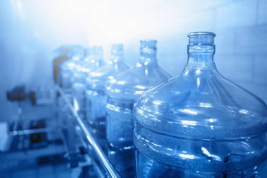Su şişeleme hattı plastik şişelerle ya da su fabrikası üretiminde galonlarla, mavi tonlu ve seçici odaklı.