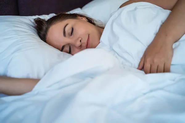 Ung vacker flicka eller kvinna sover ensam i stor säng, närbild — Stockfoto