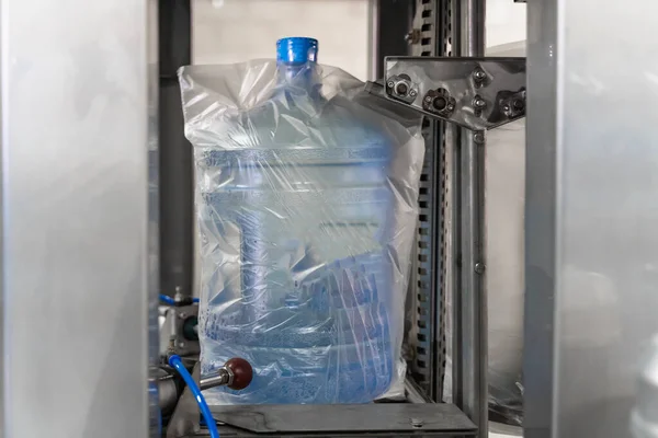 Automatische Verpackung von Plastikflaschen mit sauberem Trinkwasser in Plastik oder Zellophanbeutel in der Fabrik — Stockfoto