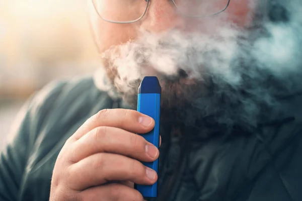 Adam yeni Vape Pod Sistemi içiyor, nefes alıyor ve nefes veriyor elektronik sigara buharı, buhar konsepti