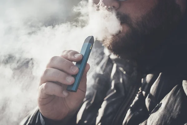 인간은 새로운 비디오 포드 시스템 을 흡연하고, 전자 담배의 증기를 들이마시고 내쉰다. — 스톡 사진