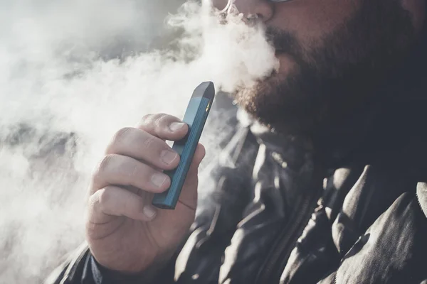 Adam yeni Vape Pod Sistemi içiyor, nefes alıyor ve nefes veriyor elektronik sigara buharı, buhar konsepti