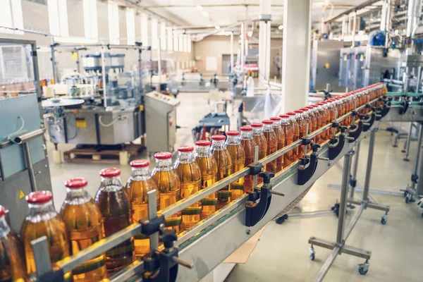 Cinta transportadora, jugo en botellas de vidrio en la planta de bebidas o en el interior de la fábrica, línea de producción de fabricación industrial —  Fotos de Stock