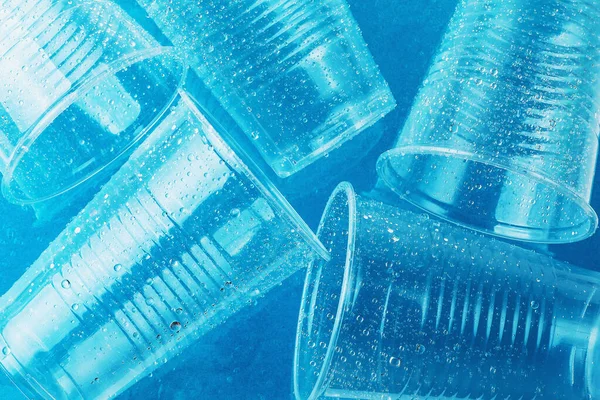 빈 투명 한 일회용 플라스틱 유리 방울에 물 밝은 파란색 배경에, 평면도 — 스톡 사진