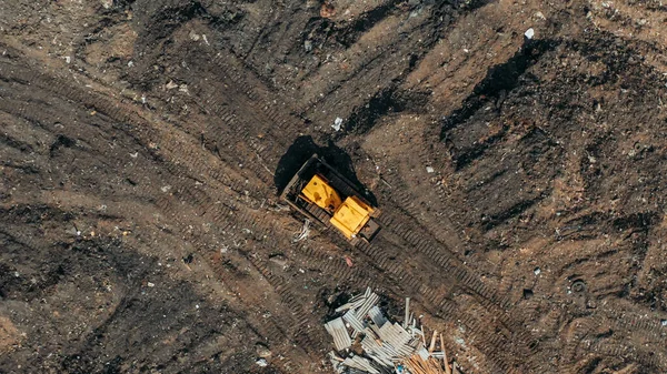 Yellow excavator or bulldozer on city dump yard, aerial or top view from drone — Stock Photo, Image