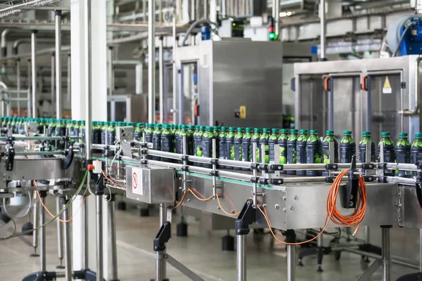 Línea transportadora con botellas de plástico de jugo en equipos modernos de fábrica. Interior de la planta de fabricación de bebidas —  Fotos de Stock