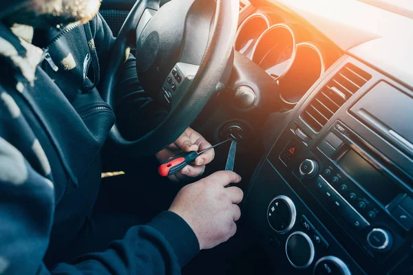 Penjahat berkerudung mencoba mencuri mobil, merusak kunci tanpa kunci untuk menyalakan mesin mobil — Stok Foto