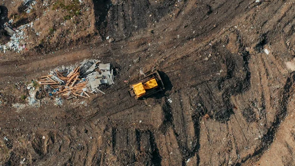 Yellow excavator or bulldozer on city dump yard, aerial or top view from drone — Stock Photo, Image