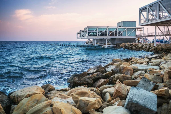 Limassol beira-mar com pedras amarelas, mar azul e cafés vazios e bares ao pôr do sol, Chipre — Fotografia de Stock