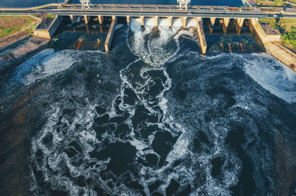 Гидроэлектростанция или гидроэлектростанция на водохранилище, вид с беспилотника. Дренаж воды через ворота, гидроэнергия
