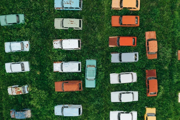 Aerial top view of many old retro rusty abandoned cars in green field, cemetery of vintage cars — Stock fotografie
