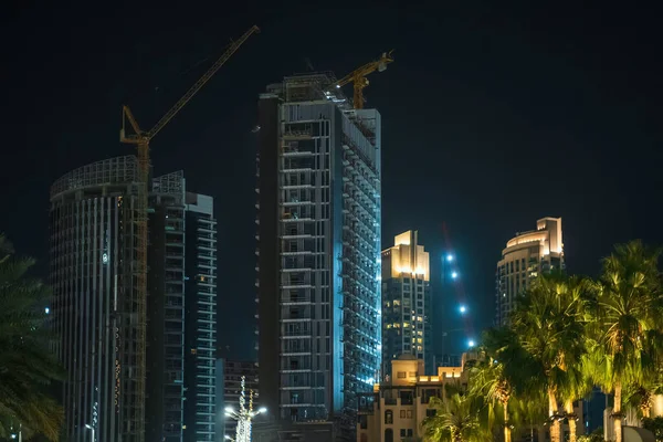 Nueva obra de construcción de gran altura en Dubái por la noche. Concepto de desarrollo rápido Dubai — Foto de Stock