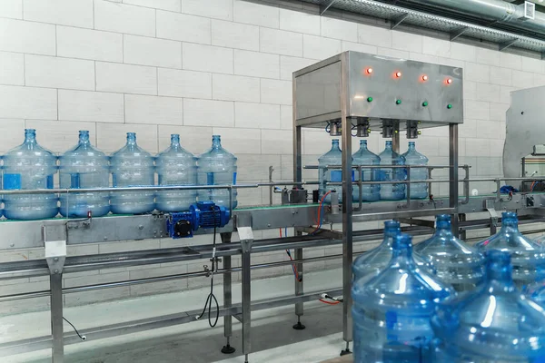 Cinta transportadora, agua en grandes botellas o galones azules, interior de la fábrica de bebidas, línea de producción industrial —  Fotos de Stock