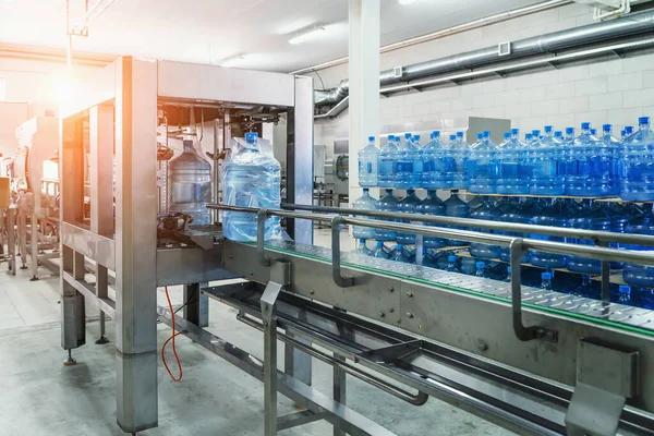 Transportband, water in grote blauwe flessen of gallons, interieur drankenfabriek, industriële productielijn — Stockfoto