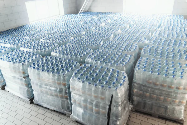 Műanyag palackok tisztított ivóvízzel raklapokon a vízgyártó üzem belsejében — Stock Fotó