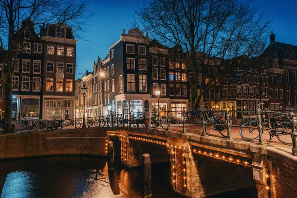 Amsterdam por la noche, puente sobre el canal de agua con luces nocturnas y casas antiguas, Amsterdam, Países Bajos — Foto de Stock