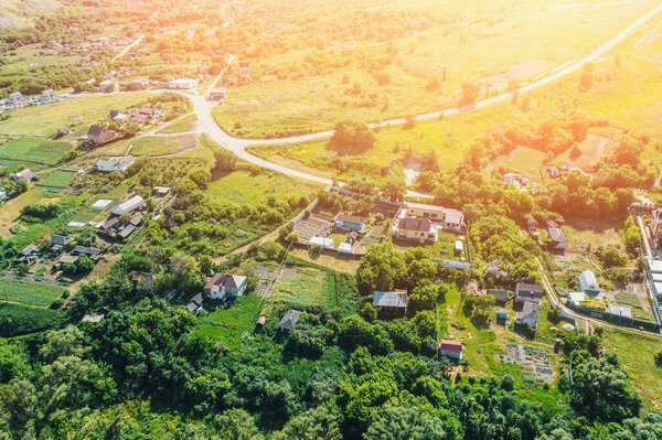 Rural village among green hills and agricultural fields in countryside , aerial view from drone.