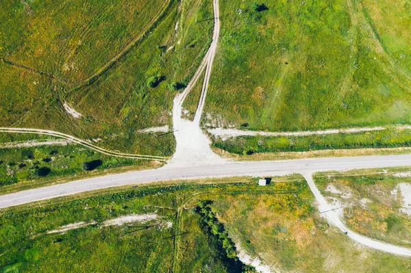 Vue aérienne de la route entre les collines verdoyantes des prés, vue du haut — Photo