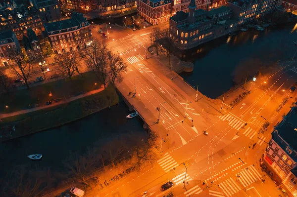 Vista aérea de la noche Amsterdam intersección carretera de la ciudad con puente y canal de agua, vista desde arriba — Foto de Stock