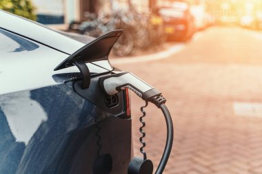 Şehir caddesinde modern elektrikli araba şarj ediliyor. Kapatın. Yenilik ve gelecekteki ulaşım