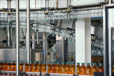 Modern içecek fabrikasında şerit ya da taşıma bandında meyve suyu bulunan plastik şişeler