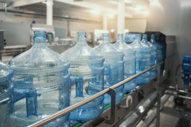 Saf içme suyunu şişelemek için su fabrikasında plastik PET şişeleri veya litrelerce üretim bandı veya taşıyıcı bant