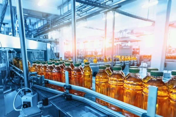 Interior de fábrica con línea de producción industrial, cinta transportadora con jugo en botellas —  Fotos de Stock