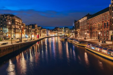 Amsterdam şehir manzarası gün batımından sonra, güzel eski Avrupa kenti Hollanda, Amstel nehrine yansıdı.