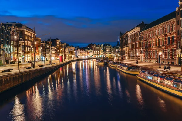 Paisaje urbano de Ámsterdam después del atardecer, hermosa ciudad europea antigua reflejada en el río Amstel por la noche, Países Bajos — Foto de Stock