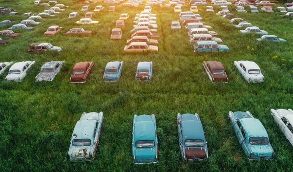 Aerial view of rows of old abandoned rusty vehicles, forgotten retro cars on green grass meadow — 스톡 사진