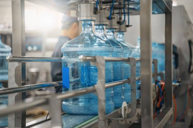 Plastik şişeler veya galonlar otomatikleştirilmiş taşıyıcı üretim hattında. Su fabrikası