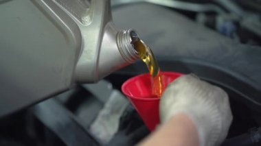 İşçi yeni sentetik motor yağını araba servisinde huniden huniye döker, düzenli yağ değişimi - otomobil sağlığı kavramı