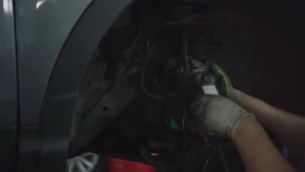 Работник режет ржавый болт в рулевом багажнике автомобиля на автосервисе с молотилкой, крупным планом — стоковое видео