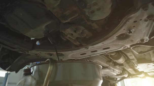 Munkás leereszti a régi motorolaj, hogy cserélje ki az autó szolgáltatás, közelről — Stock videók