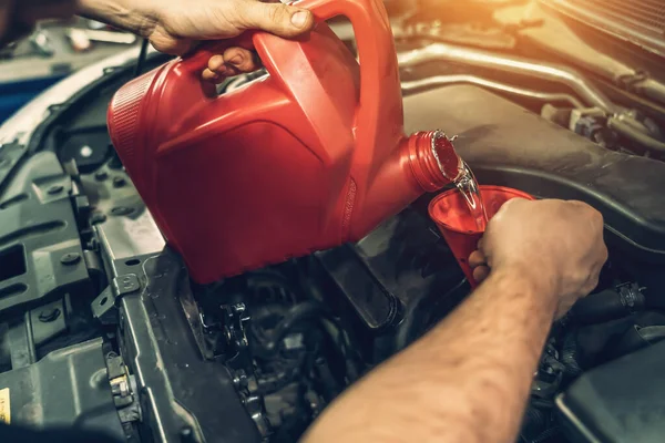 Tangan pekerja menuangkan minyak mesin ke mesin untuk menghilangkan deposit karbon, tepat waktu perubahan mobil — Stok Foto