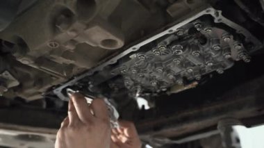 CVT vites kutusu kapanıyor, işçi elleri yağ değiştiriyor ve araba servisindeki yeni modern varyantın bakımını yapıyor.