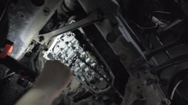CVT vites kutusu kapanıyor, işçi elleri yağ değiştiriyor ve araba servisindeki yeni modern varyantın bakımını yapıyor.