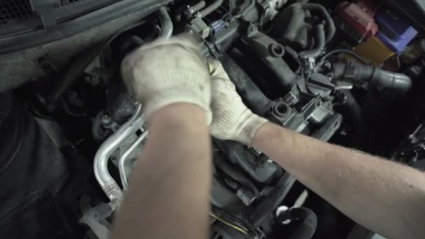 Рабочие руки меняют свечи зажигания в автомобильном двигателе в автосервисе, закрывают — стоковое видео