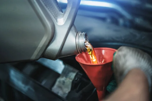 Trabalhador derrama novo óleo de motor sintético da lata em funil no serviço de carro, mudança de óleo regular conceito de saúde automática — Fotografia de Stock