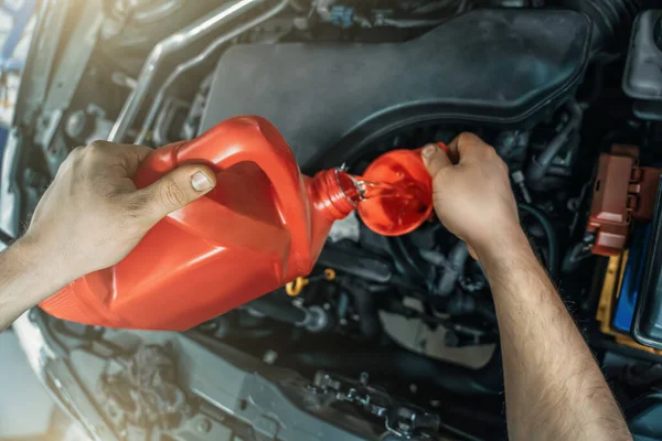 Pouring new engine oil from canister into motor funnel at car service, close up