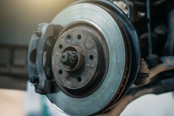 Car in car service with wheels removed for repair, front brake disc close up — Stock Photo, Image