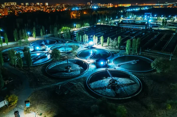 Vista aérea nocturna de la moderna planta de tratamiento de aguas residuales con piscinas redondas para la limpieza de aguas residuales, tiro con drones — Foto de Stock