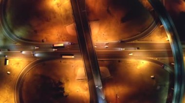 Gece kentinde köprülerle otoyol ve yol kavşağı, İHA 'dan hava manzarası, araba trafiği, ulaşım ve kentsel gelişim kavramı