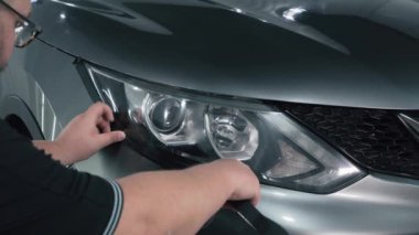 İşçi far optiklerinin üzerinde özel bantla, parlatmaya hazırlanıyor.
