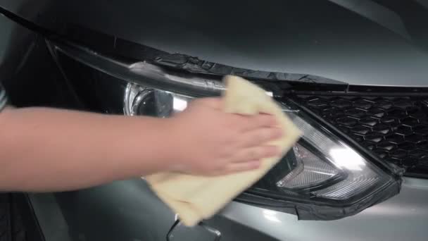Szczegóły samochodu. Robotnicze polerowanie ręcznikiem z mikrofibry tylne światło optyczne samochodu w warsztacie samochodowym — Wideo stockowe