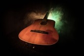 Hudební koncept. Akustická kytara na tmavém pozadí pod paprsek světla s kouřem. Kytara s řetězci, zblízka. Selektivní fokus. Účinky požáru.